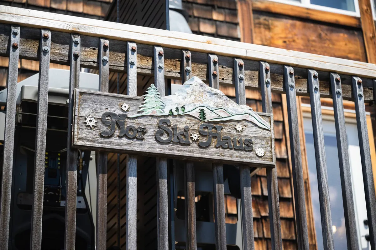 The exterior image captures the welcoming signage of 'Not Ski Haus,' adorned with mountain and tree designs, set against a backdrop suggestive of the Mt. Hood area. The sign marks the property entrance, hinting at the outdoor adventures and pet-friendly experiences that await.
