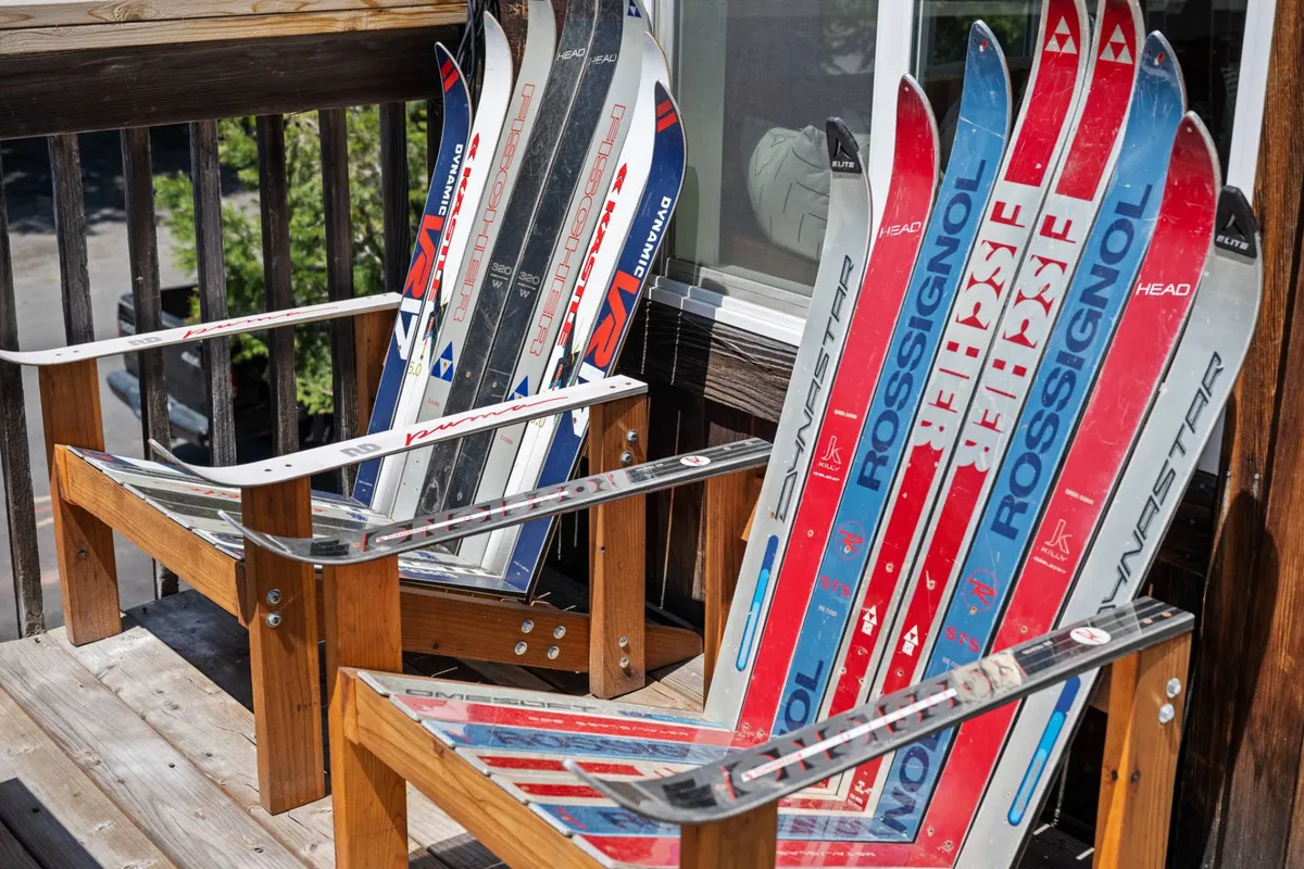 A playful deck arrangement with ski chairs and decorative skis, looking out onto the scenic mountain landscape. The seating is positioned for taking in sunset views or sharing drinks, creating a welcoming spot for group relaxation.